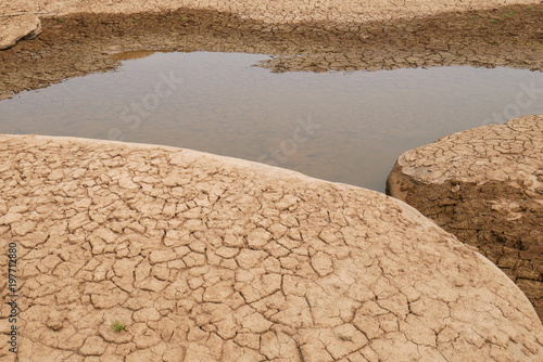 Cracked mud and shallow pond with nobody, global warming concept and background