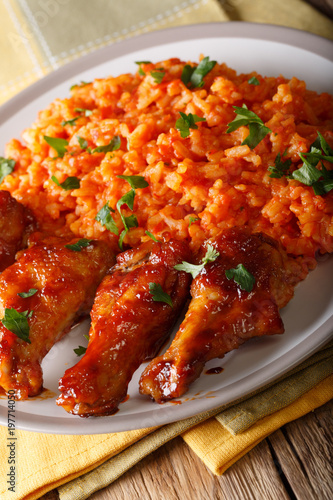 Classic Nigerian Jollof Rice with fried chicken wings close-up. Vertical photo