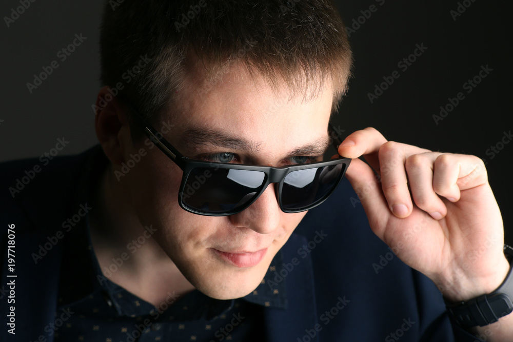 Young handsome man with glasses on dark background