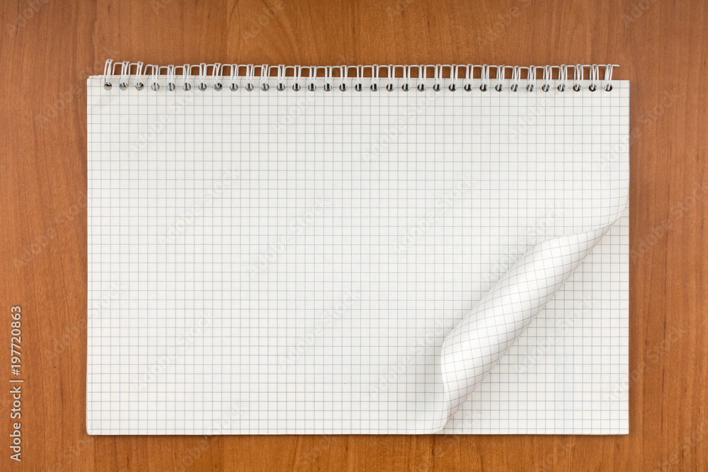 Notepad on a spiral with a curled sheet lying on a table.