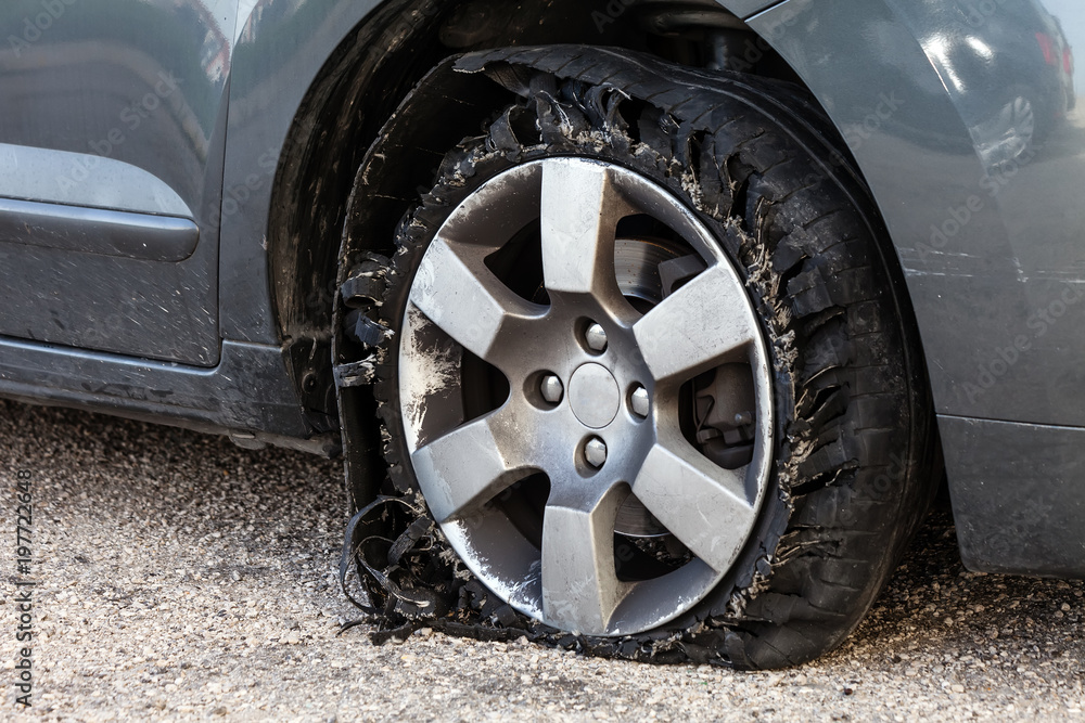 Destroyed blown out tire with exploded, shredded and damaged rubber on a modern suv automobile. Flat low profile tyre on an alloy rim, ripped open in pieces with visible interior.
