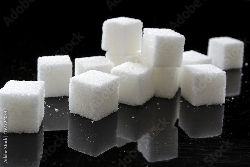 Sugar cubes on a black mirror table, black background