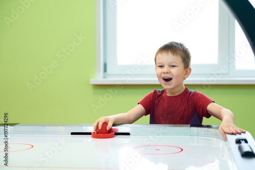 Happy boy playing air hockey with passion