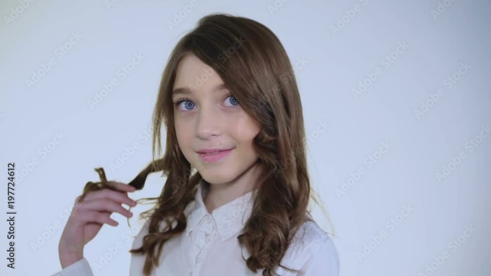Young pretty modest girl plays her hair and smiles at camera Young pretty modest girl plays her hair and smiles at camera