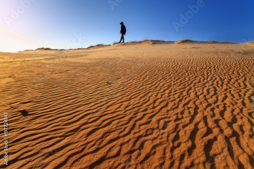 walking through the dunes  person looking towards the sun