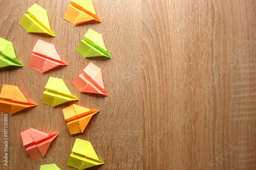 Multicolored origami planes on wooden background with copy space for your text or object
