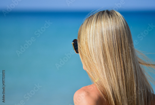 Closeup of blond hair girl looking something in the distance with wind in her hair. Woman body part on the beach - no visible face photo