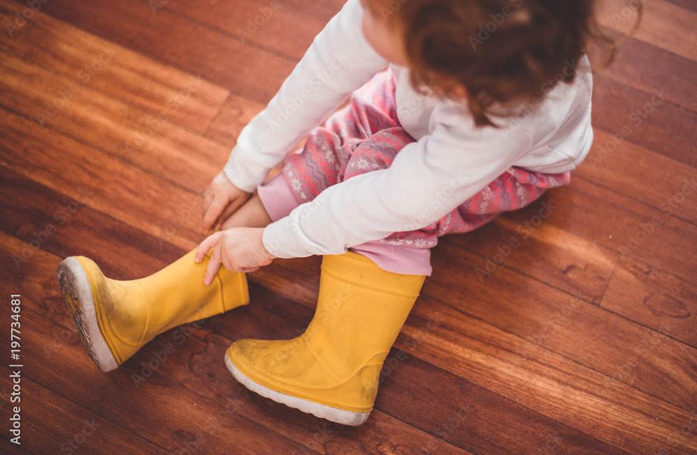 Niña poniéndose sus botas de agua amarillas Stock Photo | Adobe Stock