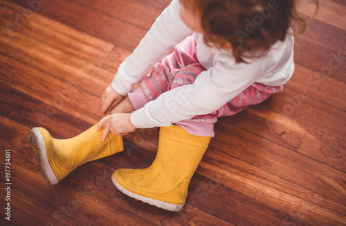 Niña poniéndose sus botas de agua amarillas