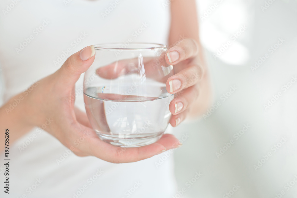 Female hands holding a clear glass of water. Slime body on background. Female hands holding a clear glass of water. Slime body on background.