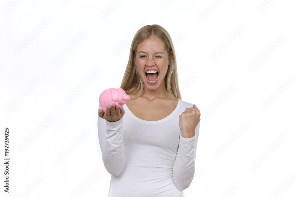 Hübsche blone Frau hält ein Sparschwein in den Händen ballt eine Faust und ist begeistert Hübsche blone Frau hält ein Sparschwein in den Händen ballt eine Faust und ist begeistert