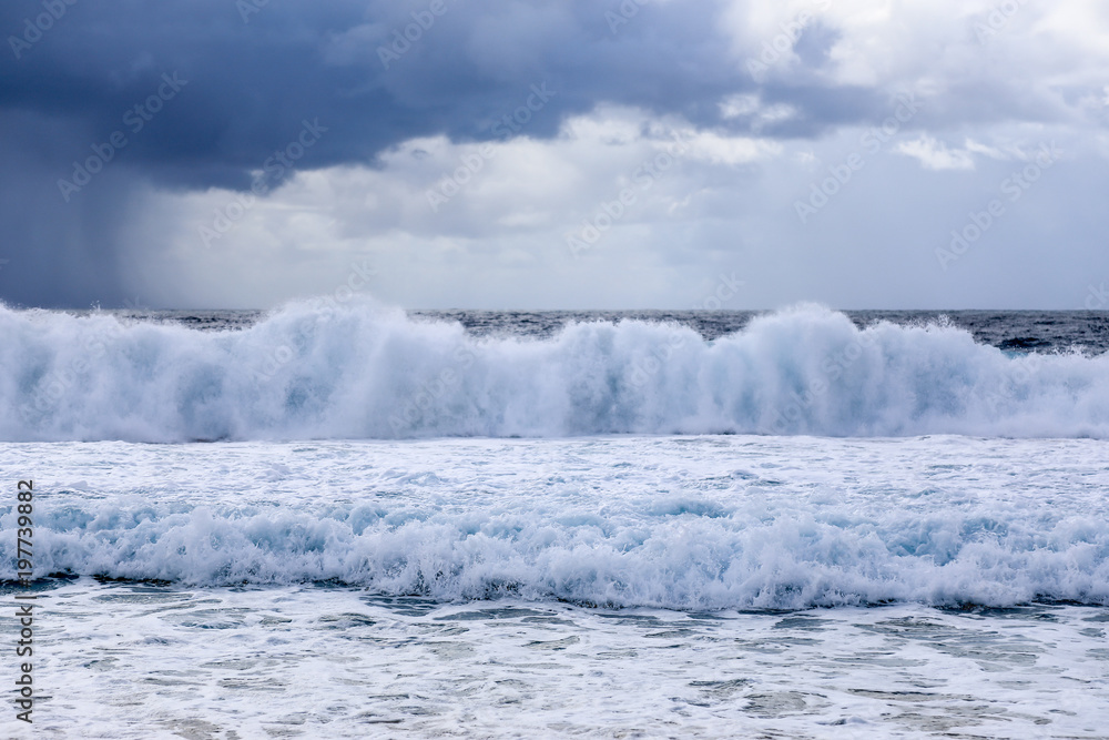 Waves crashing in ocean against stormy sky