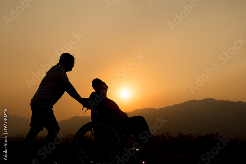 Happy boy in wheelchair and sister on sunset. Happy disabled child concept