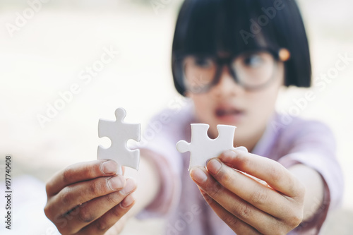 Jigsaw Puzzle Game: Hands of a little girl holding and matching two pieces of a puzzle.