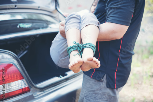 Man kidnapped little girl with rope tied legs and hands at the trunk photo