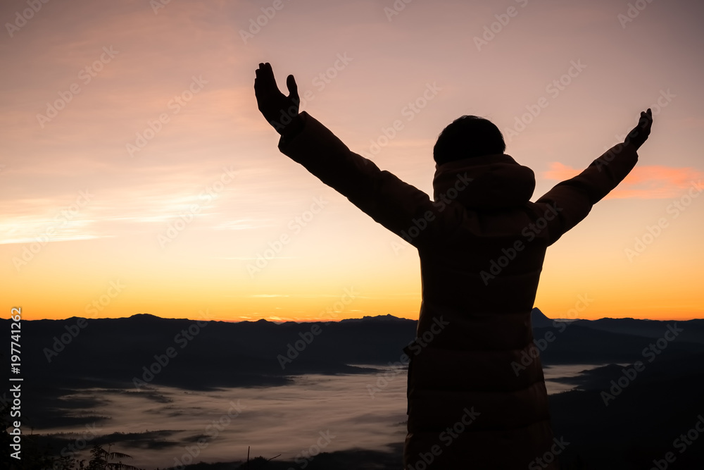 Silhouette of a man with hands raised in the sunset. Religion concept.