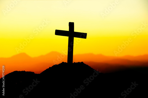 Concept conceptual cross religion symbol silhouette in nature over sunset or sunrise sky