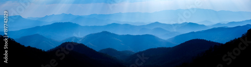 Beautiful landscape of blue mountains layers during sunset with sunrays