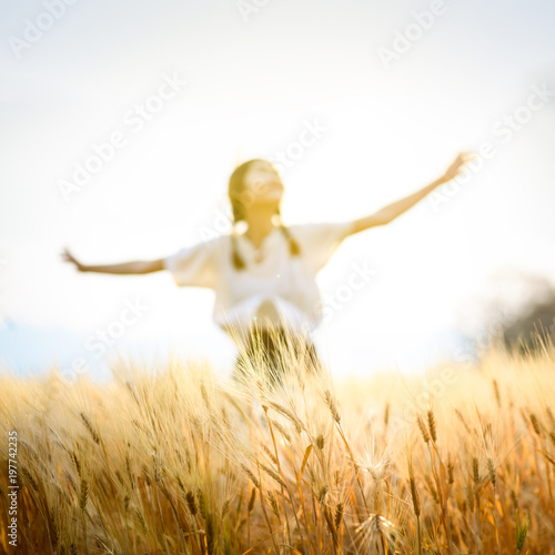 Happy woman relaxing on wheat field in summer sunset sky outdoor. People freedom open arms