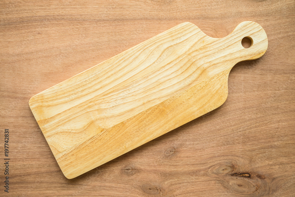 Top view of unused brand new brown handmade wooden cutting board on wooden table background