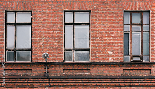 Fragment of the facade of an old brick building. High Windows and textured materials