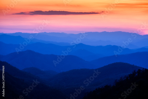 Dramatic sunset and sunrise sky and clouds over blue mountains layers