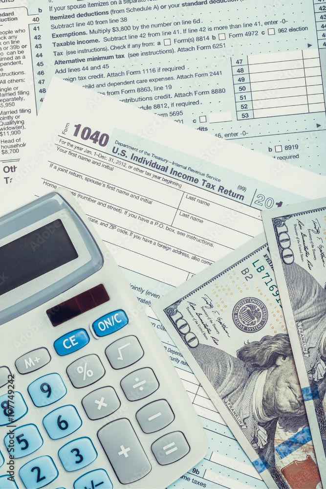 United States of America Tax Form 1040 with calculator and US dollars over it - close up studio shot United States of America Tax Form 1040 with calculator and US dollars over it - close up studio shot