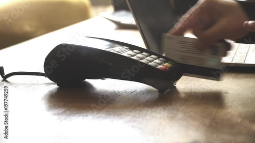woman hand pushing the button and swipe credit card payment on pos terminal standing on wooden desk.