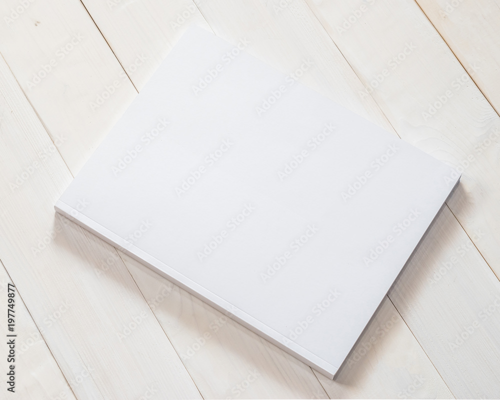 Blank book cover mockup template with page front side on white surface on wood table Blank book cover mockup template with page front side on white surface on wood table