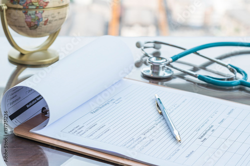 Doctor's working table with pen for writing on patient's discharge blank paper form, medical prescription, stethoscope on desk.