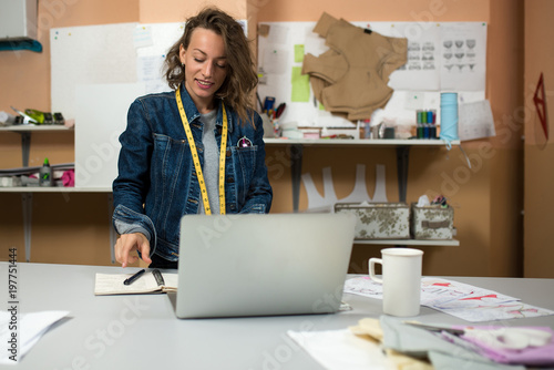 The designer of clothes works in the workshop in front of the laptop
