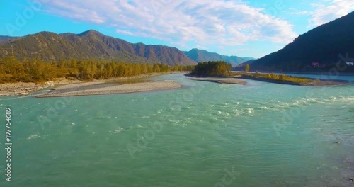 4k (UHD) aerial view. Low flight over fresh cold mountain river at cloudy summer morning. Green trees and sun rays on horisont. Fast horizontal movement