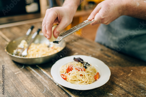 Chef grates cheese in to the plate with fettuccine