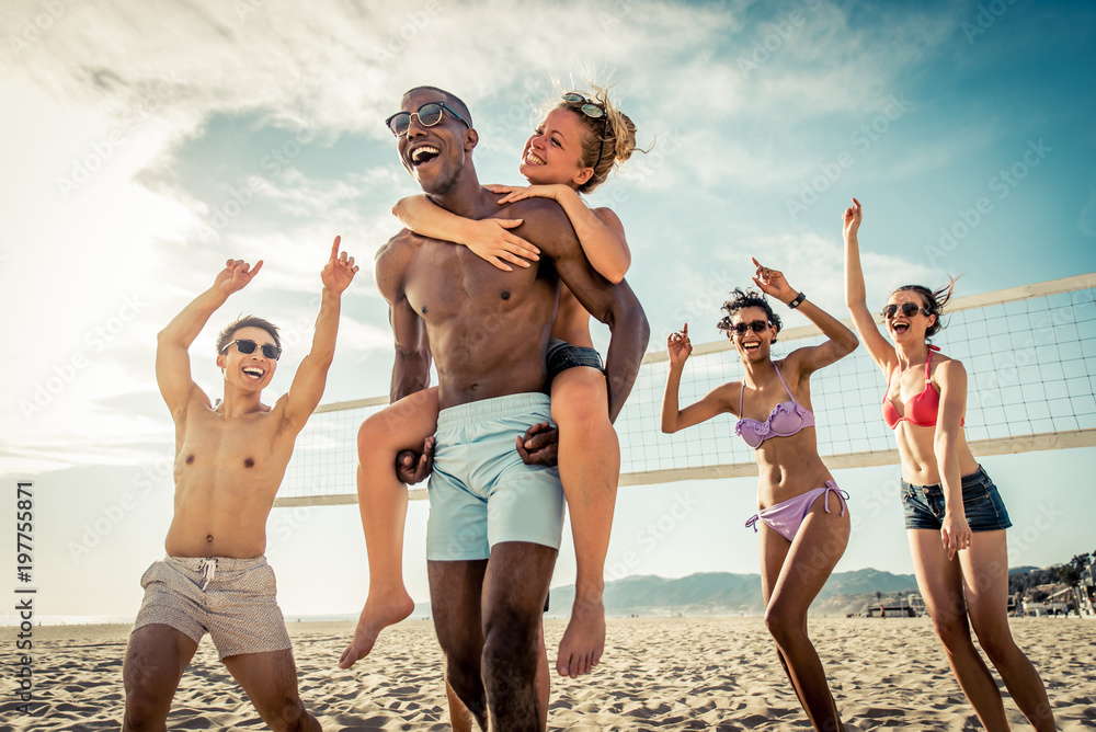 Fototapeta premium Grupa przyjaciół grających w siatkówkę plażową na plaży.
