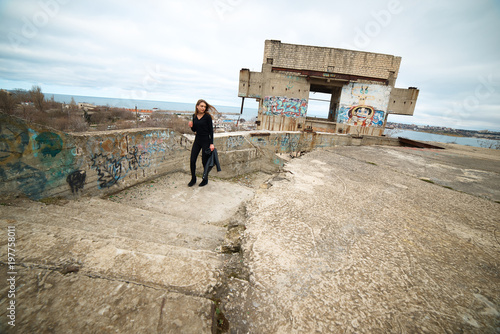 Young slim brunette on a ruins of abandoned building