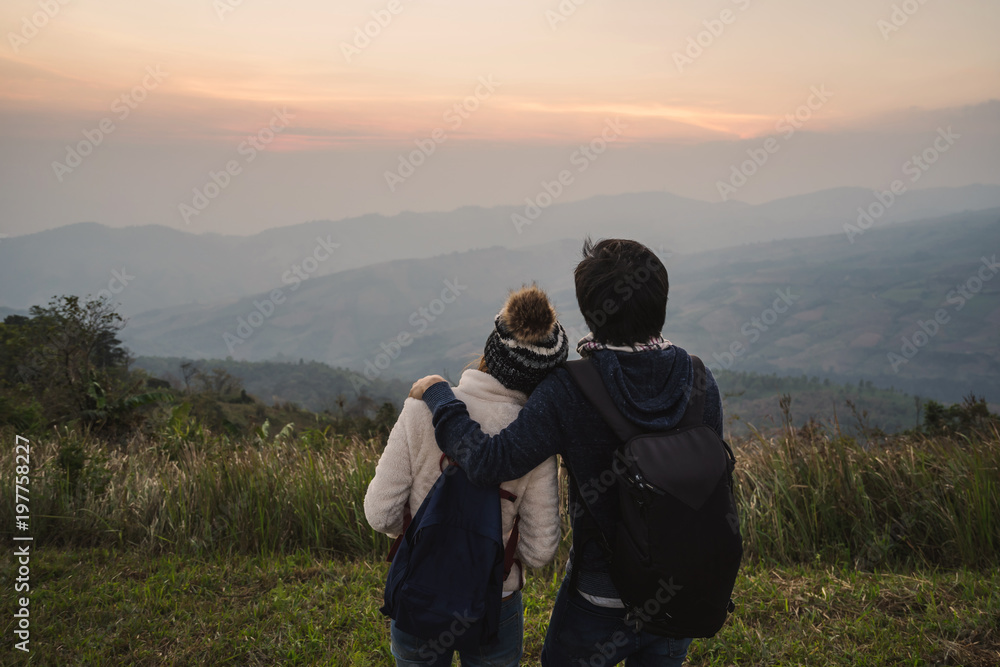 Loving couple embracing on the mountain at sunset.