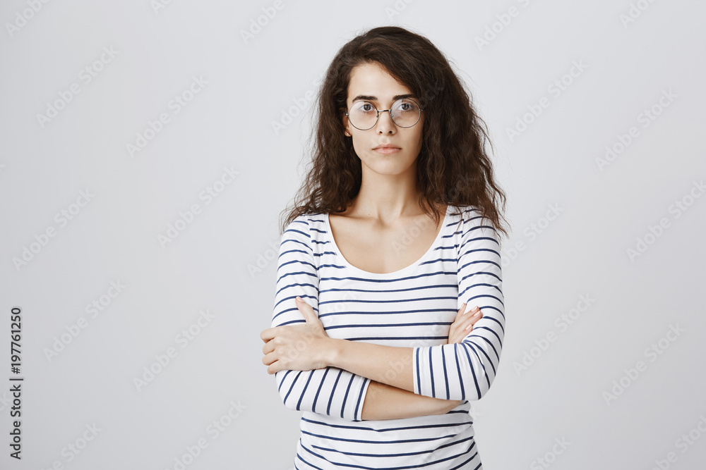 Excellent pupil being serious about university studies. Smart good-looking caucasian woman in glasses with curly hair crossing hands on chest and staring focused at camera, feeling confident Excellent pupil being serious about university studies. Smart good-looking caucasian woman in glasses with curly hair crossing hands on chest and staring focused at camera, feeling confident