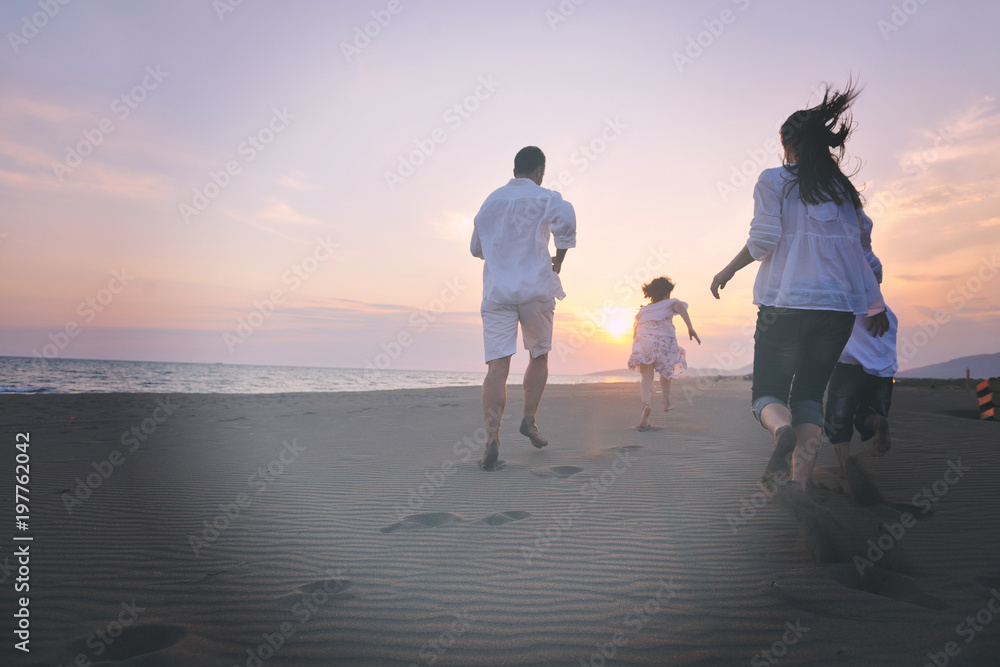 Fototapeta premium szczęśliwa młoda rodzina zabawy na plaży o zachodzie słońca