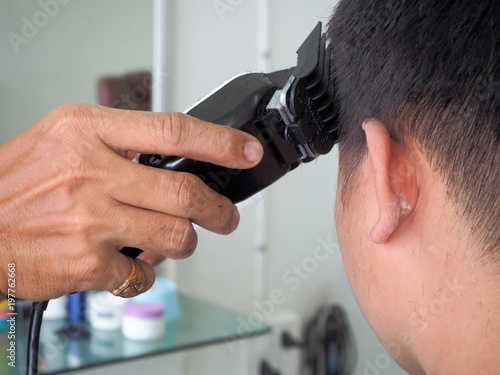 man getting haircut at barber shop. Hairdresser cutting hair of customer at salon.