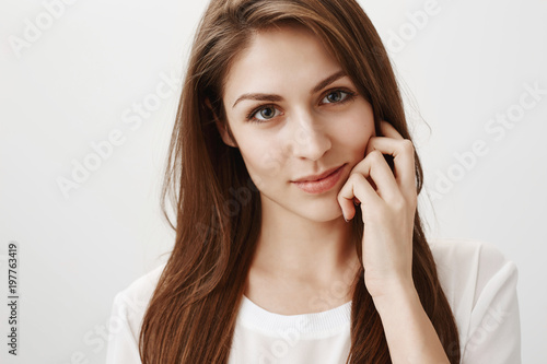 Natural beauty and people concept. Portrait of attractive caucasian brunette expressing sexuality, smiling gently and touching face with fingers, gazing at camera with sensual look