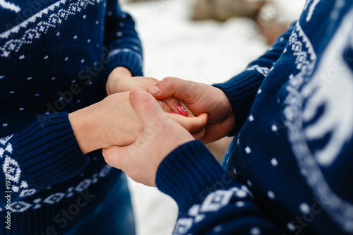 Boyfriend and girlfriend traveling lifestyle, tranquility and contamination on a cold winter vacation. Young couple holding each other's hands in winter warm sweaters and jeans. © korchemkin