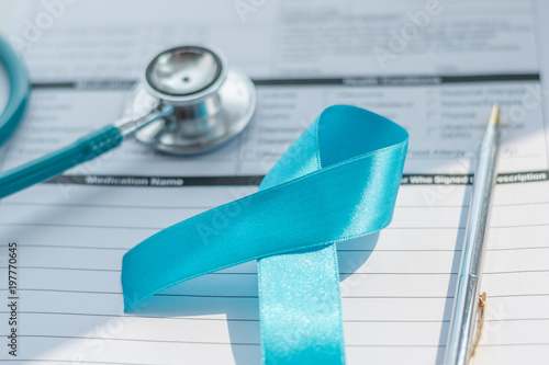 Blue ribbon symbolic of prostate cancer awareness campaign and men's health in November month on  patients health record  form with doctor stethoscope. photo