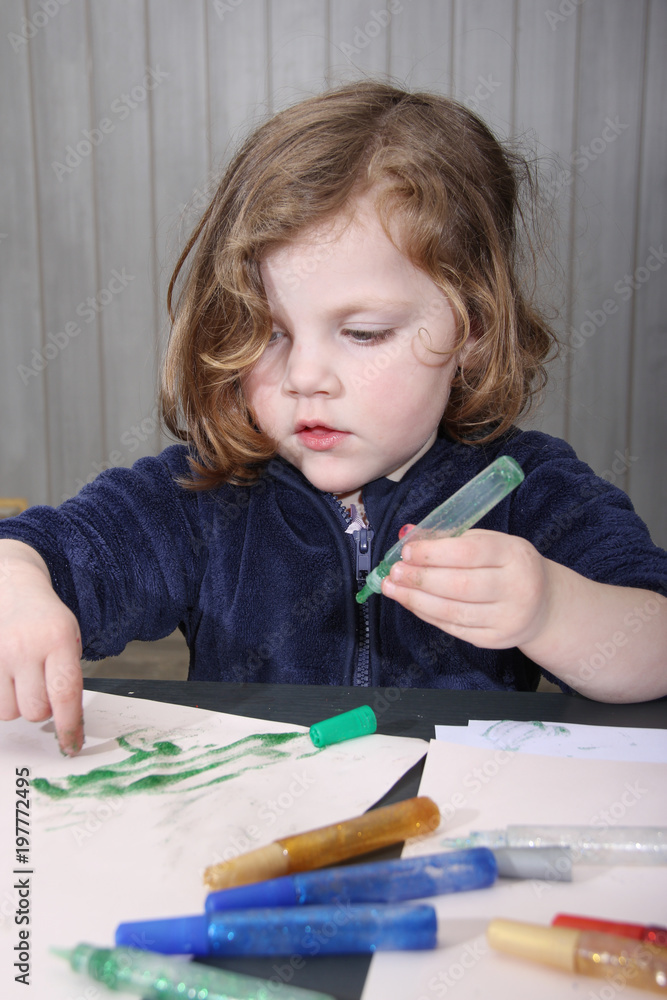 little blonde girl painting with her hands on a paper at home. little blonde girl painting with her hands on a paper at home.