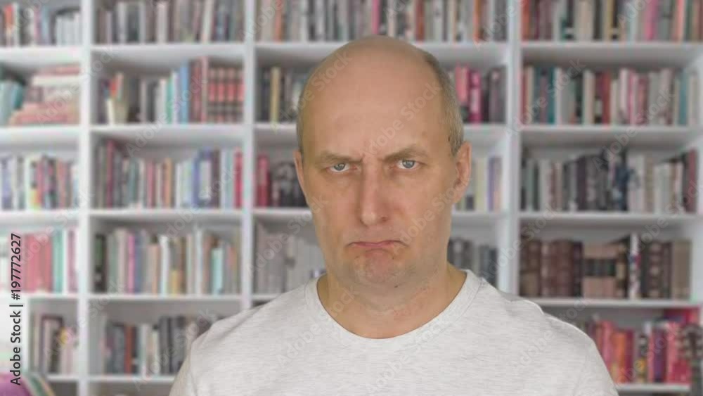 Portrait angry man face looking into camera on bookcase background Portrait angry man face looking into camera on bookcase background