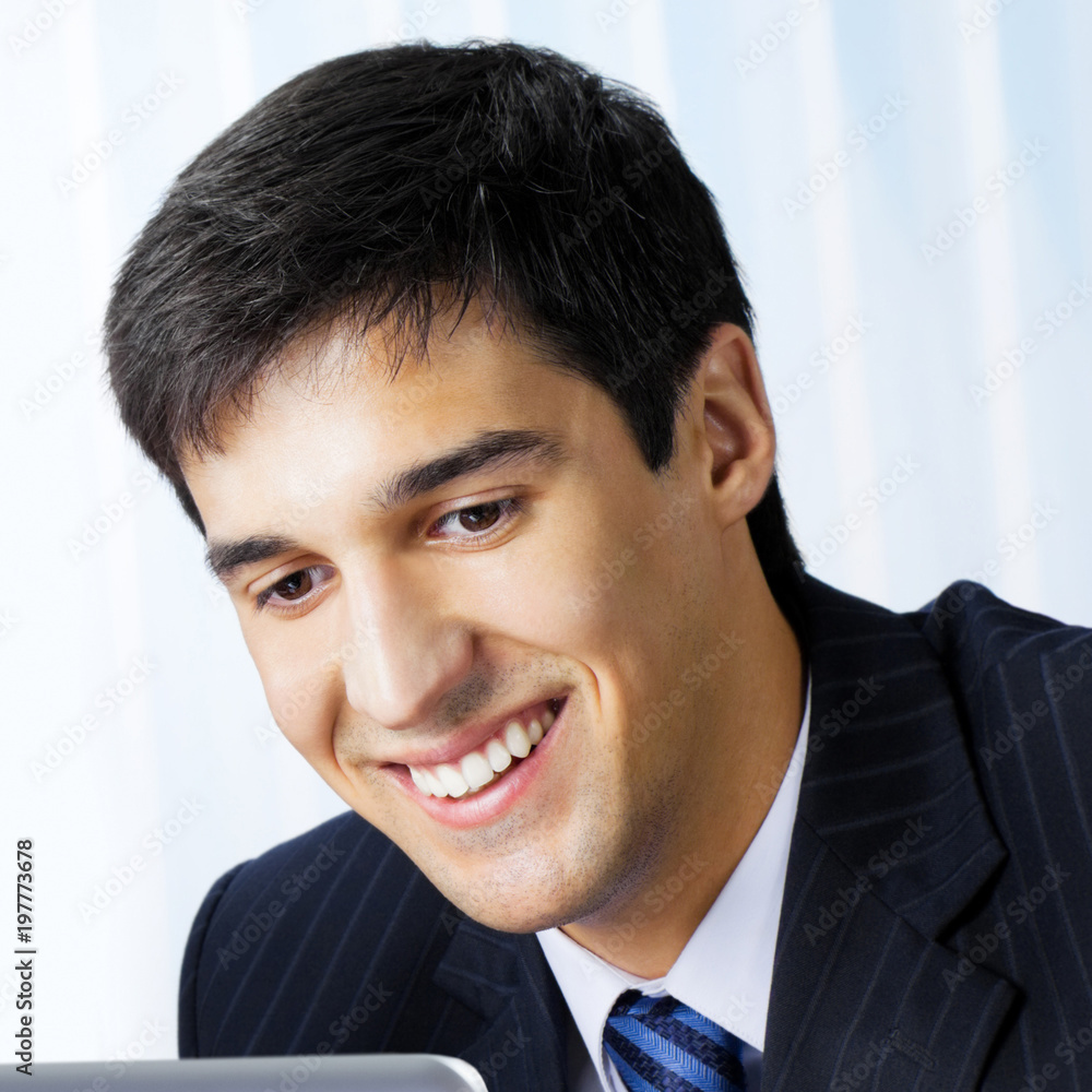 Smiling businessman working with laptop at office Smiling businessman working with laptop at office