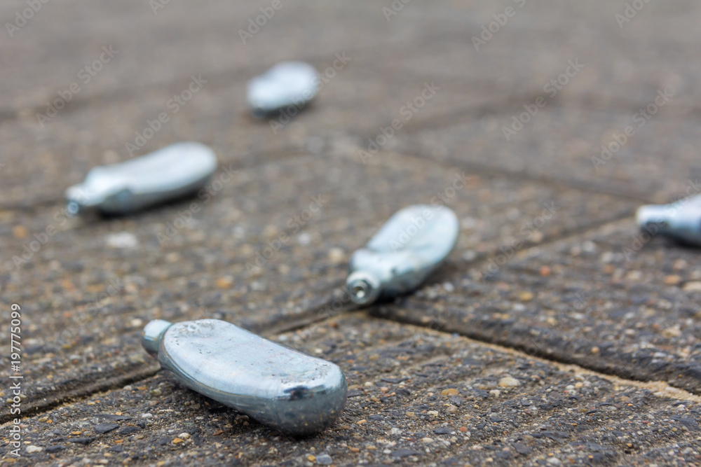 empty nitrous oxide bulbs lying scattered on the street, also known as  laughing gas or hippie crack recreational drug, lying scattered on the  street Stock Photo | Adobe Stock