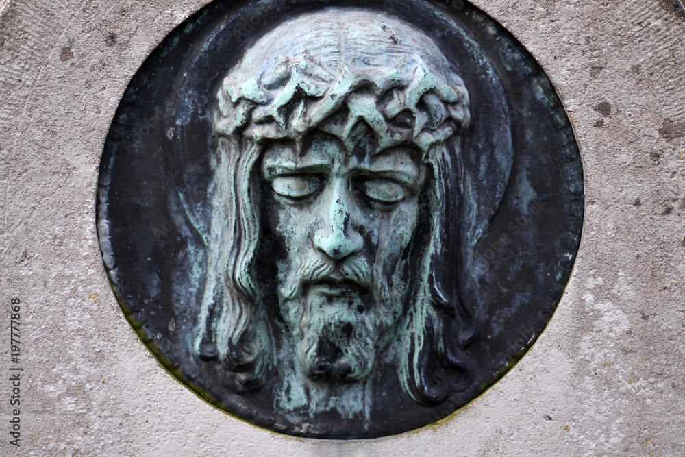 Weathered relief of Jesus christ in front of a crypt