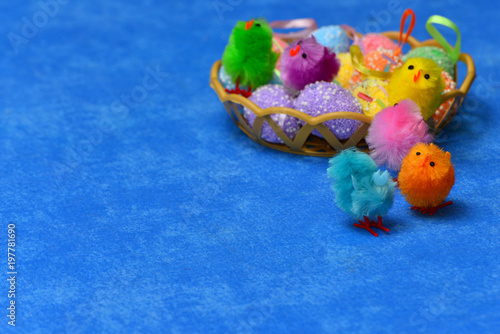 Decor of Easter eggs and chickens in a basket on a blue isolated background. The chickens are jumping into the basket. photo