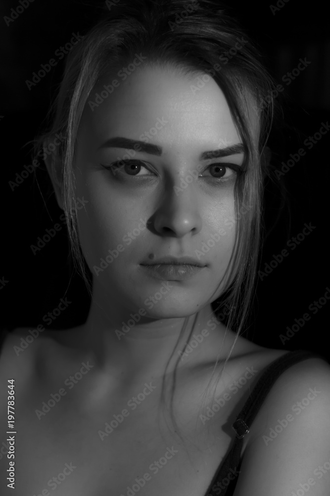 Beautiful sensual blonde girl. Close-up of an attractive girl of European appearance on dark background.