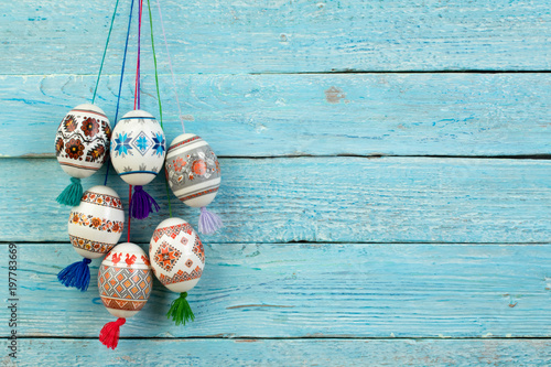 Happy Easter card. Colorful shiny easter eggs on blue wooden table background. Copy space for text.
